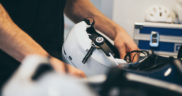 A white Sweet Protection ski helmet being handled during the design process and showing a dial fit system