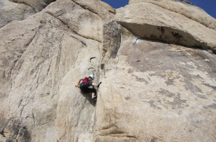 a climber scales a vertical rock face