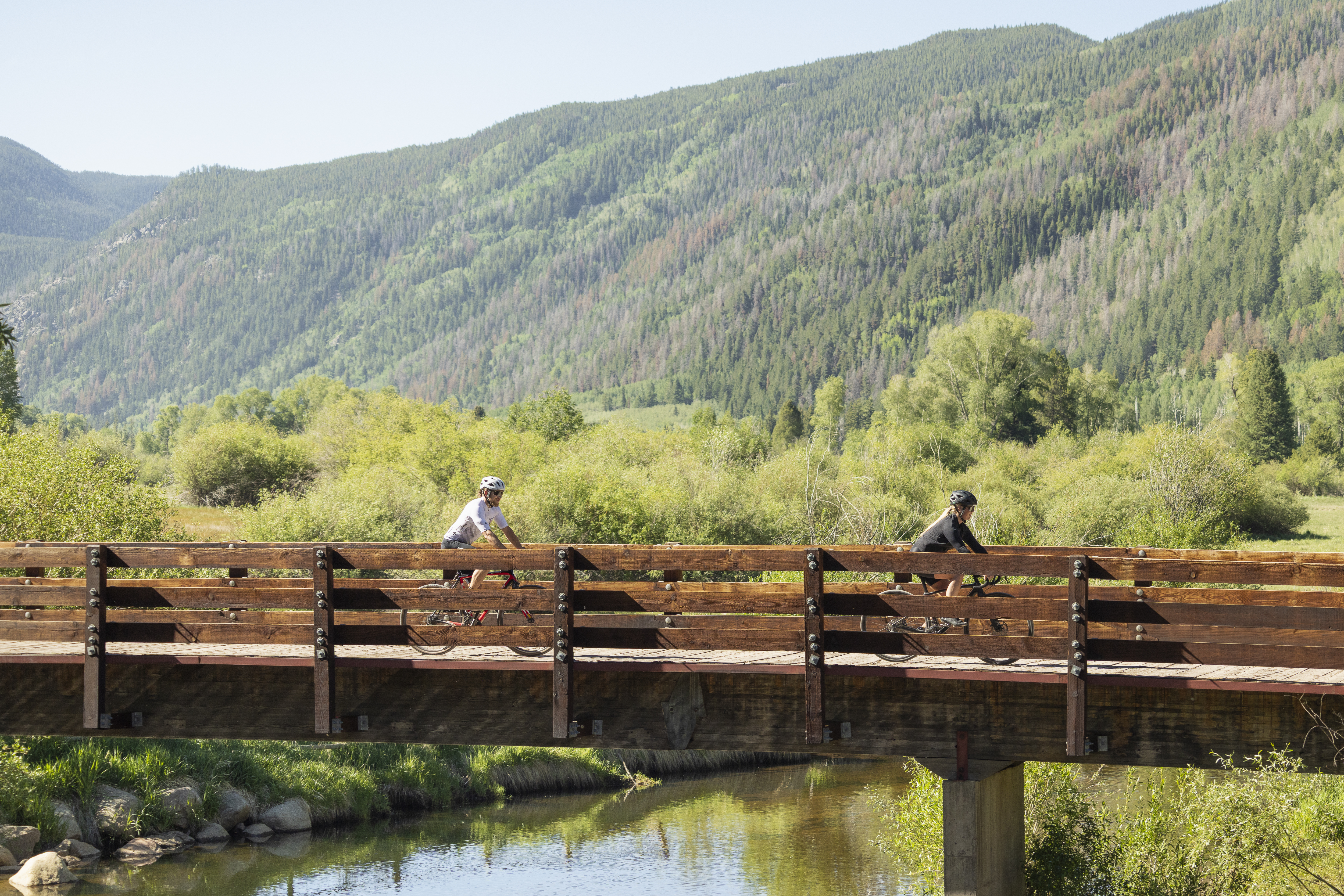 Two cyclists riding a gravel trail along a creek