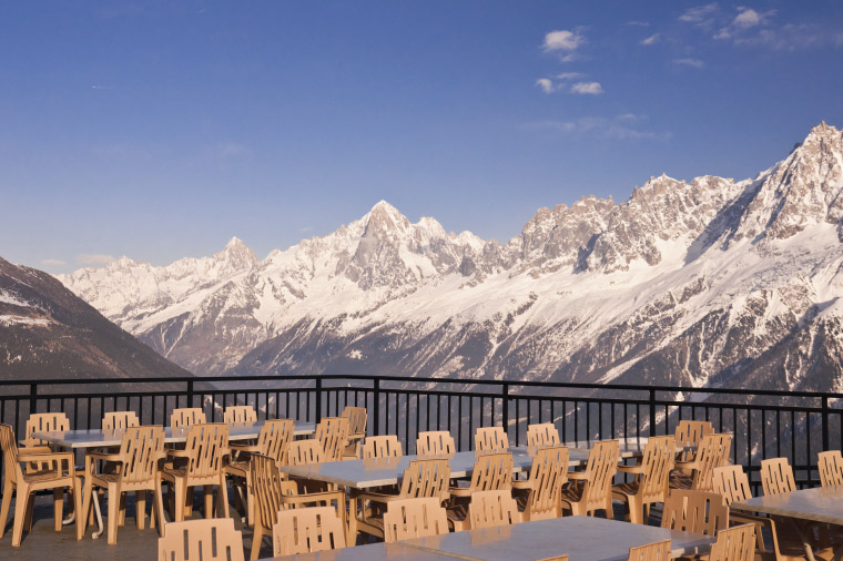 A ski lodge deck is empty with mountains in the background