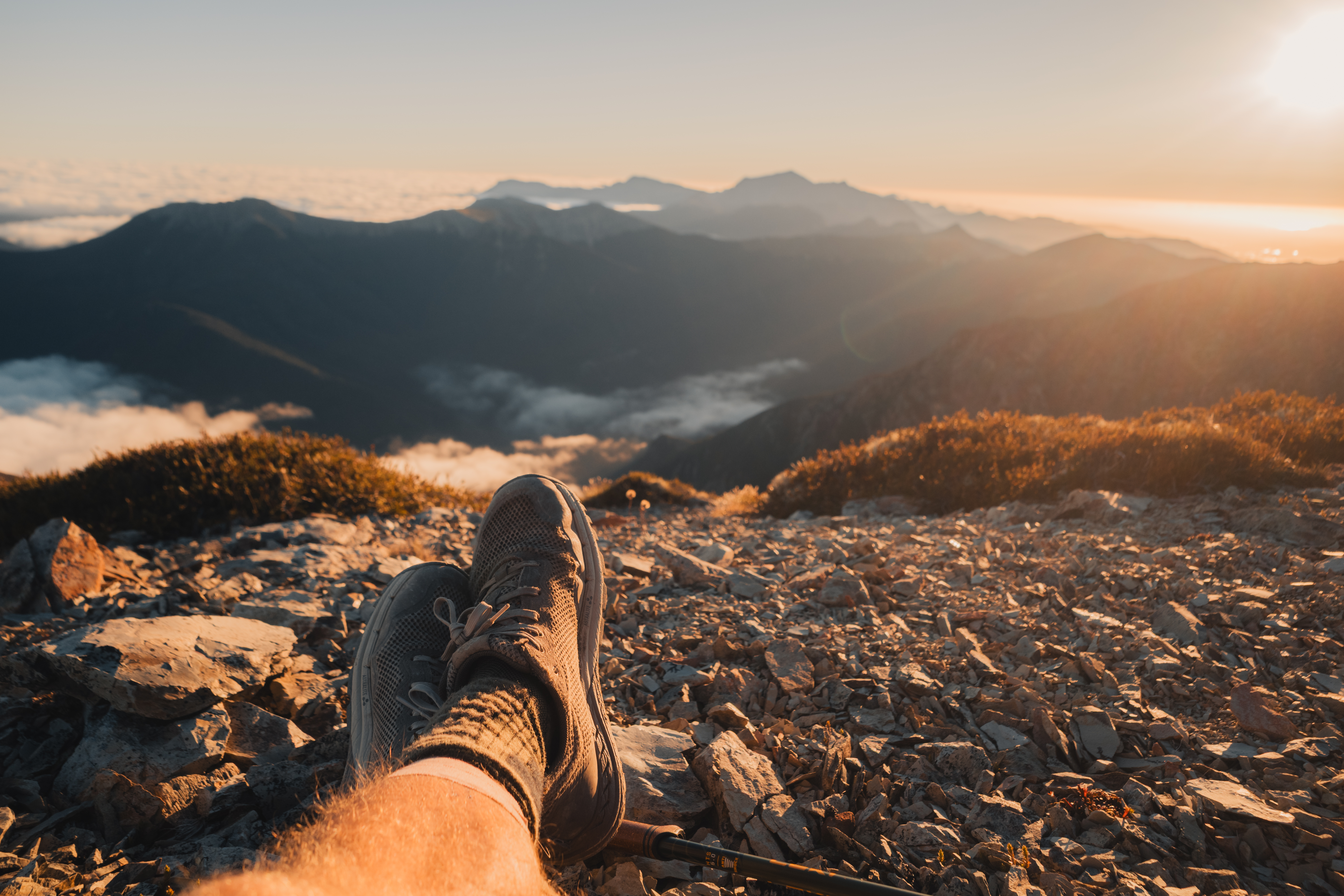 Astral hiking shoes atop a summit near sunset